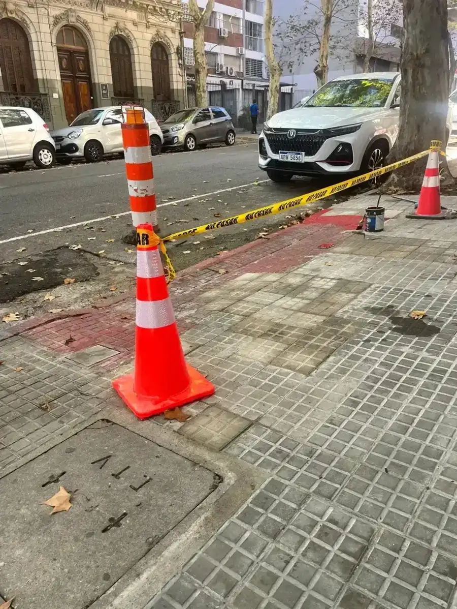 Vereda nueva terminada sobre la calle, señalizada con conos y cinta de obra