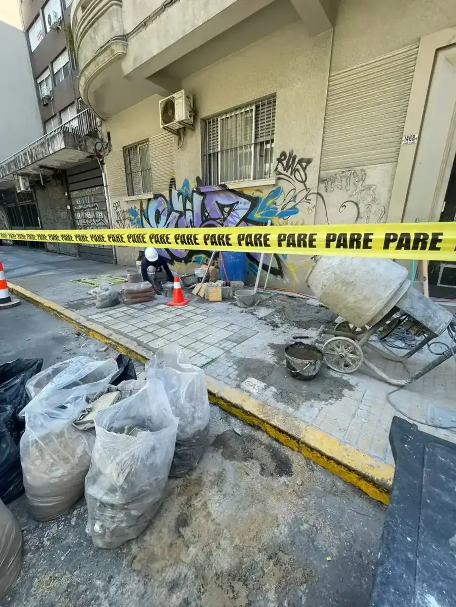 Hormigonera y materiales en obra de vereda frente a un edificio