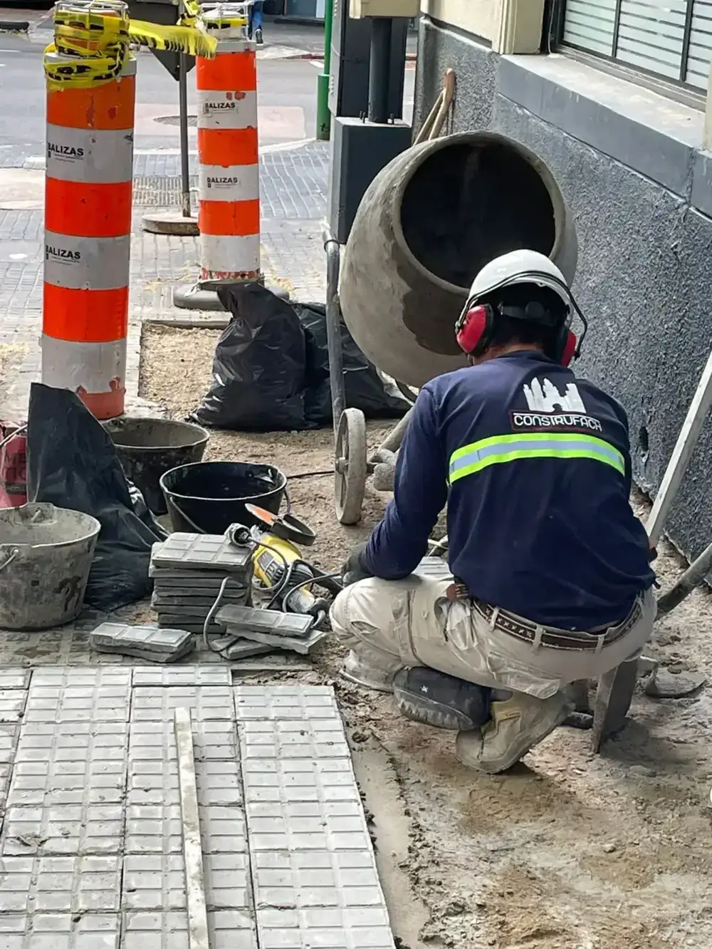 Operario cortando y ajustando baldosas de vereda con amoladora